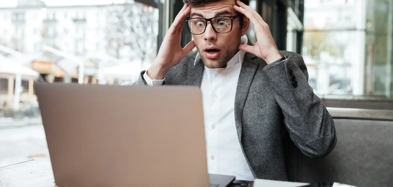 hombre-negocios-confundido-preocupado-anteojos-sentado-junto-mesa-cafe-mientras-sostiene-cabeza-mira-computadora-portatil.png